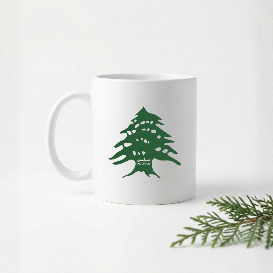 White 11 oz ceramic mug with green Lebanese cedar tree design by Nafas on a white background