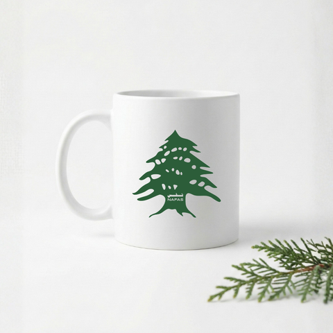 White 11 oz ceramic mug with green Lebanese cedar tree design by Nafas on a white background