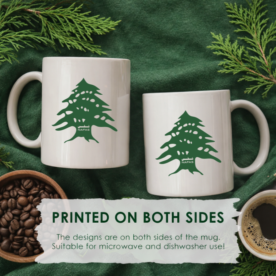 Two white 11 oz ceramic mugs with green Lebanese cedar tree designs by Nafas on a green background, showing print on both sides
