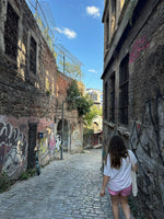 Person walking through a historic stone alley with graffiti and blue sky, used for Nafas Lebanon brand story