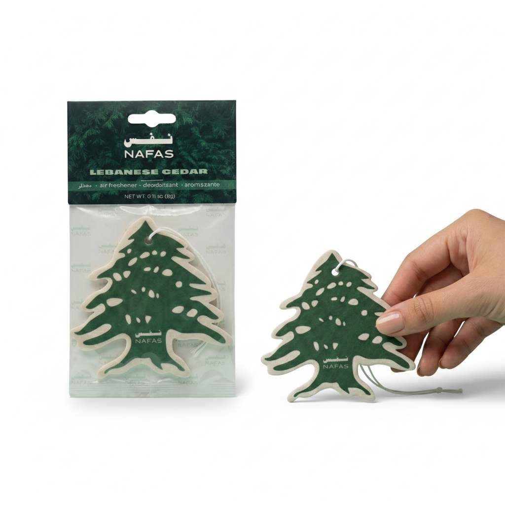 Nafas Lebanese Cedar tree-shaped car air freshener shown in branded packaging with one freshener held in hand on a white background