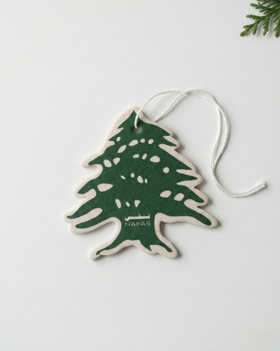 Nafas Lebanese cedar tree car air freshener with white string on a minimal white background
