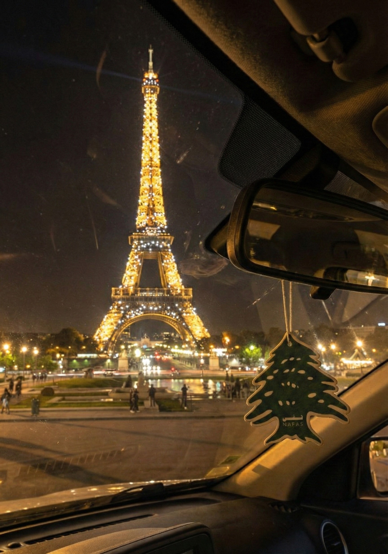 Eiffel Tower at night seen from inside a car in Paris with a Nafas Lebanese cedar air freshener hanging from the rearview mirror