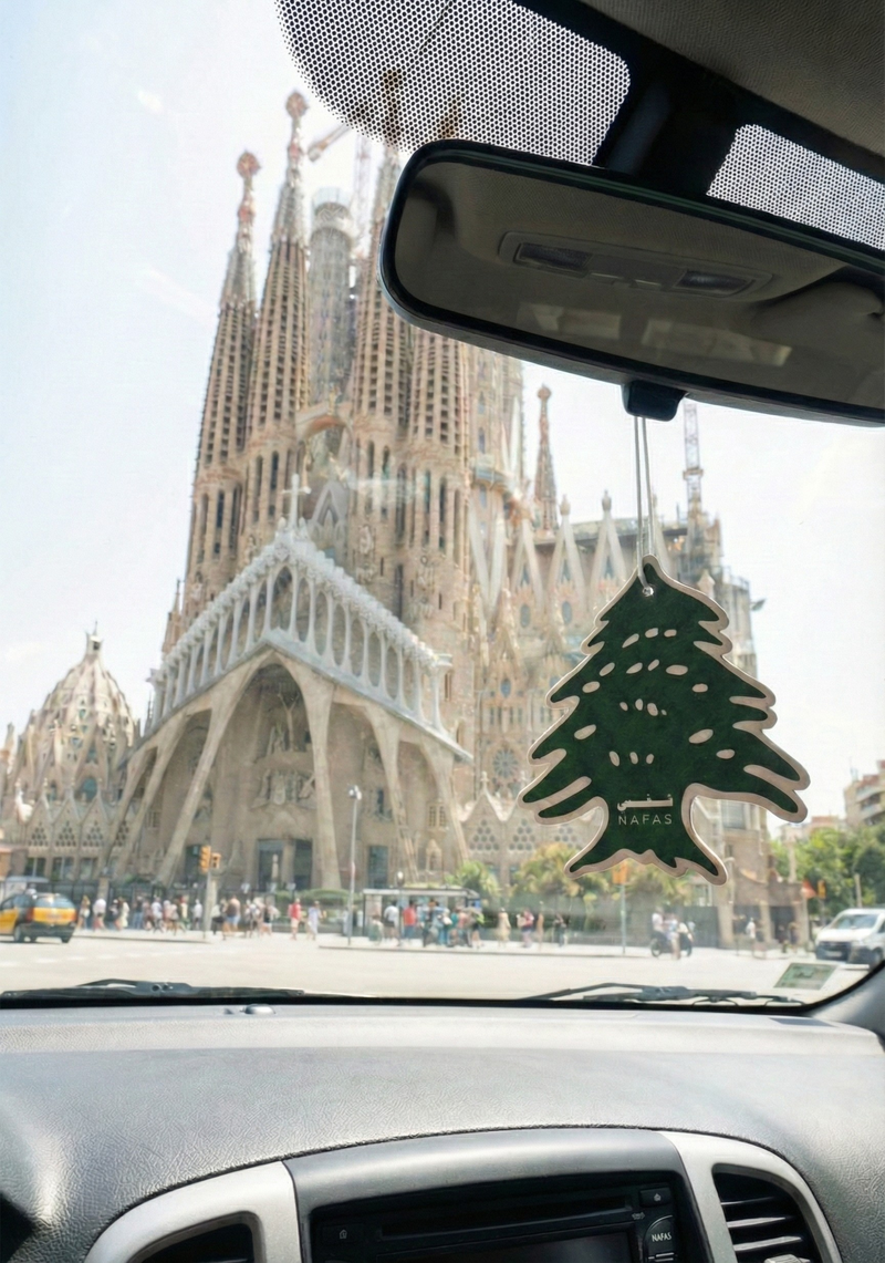 Sagrada Família in Barcelona seen from inside a car during the day with a Nafas Lebanese cedar air freshener hanging from the rearview mirror
