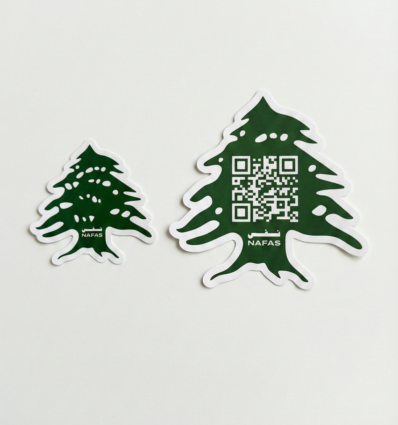 Top-down photo of Nafas cedar sticker pack: one QR code cedar sticker and one Nafas logo cedar sticker on a clean white background.